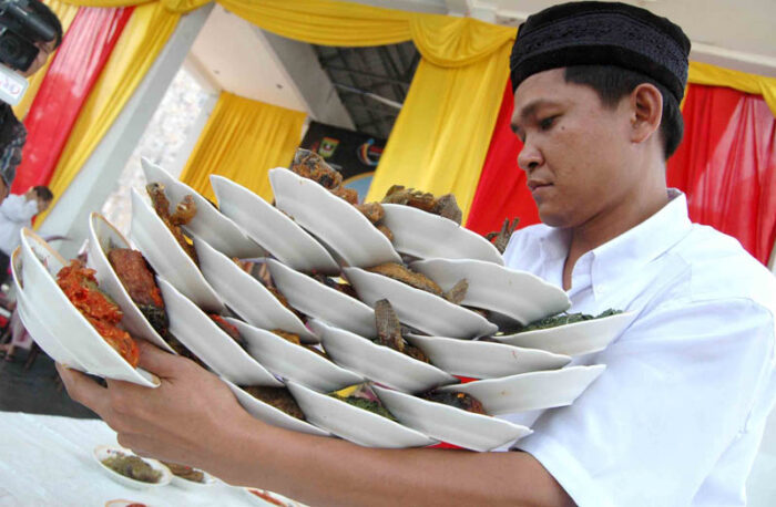 Karyawan Rumah Makan Padang Membawa Piring